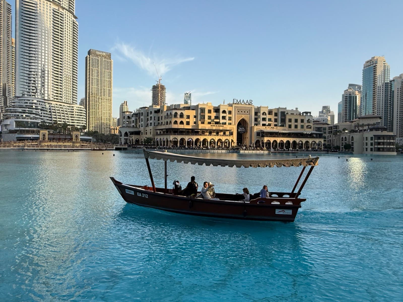 Tradiční loď abra s turisty na jezeře u Dubai Mall s mrakodrapy Downtown Dubai v pozadí