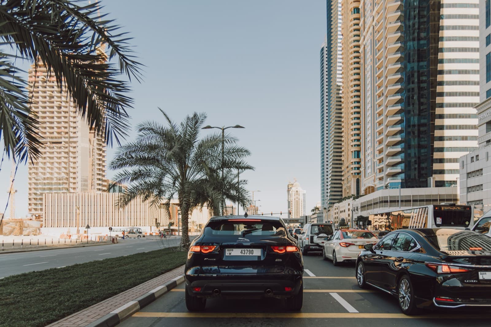 Auta v ulicích Dubai Marina mezi mrakodrapy a palmami - běžný provoz v moderní části Dubaje