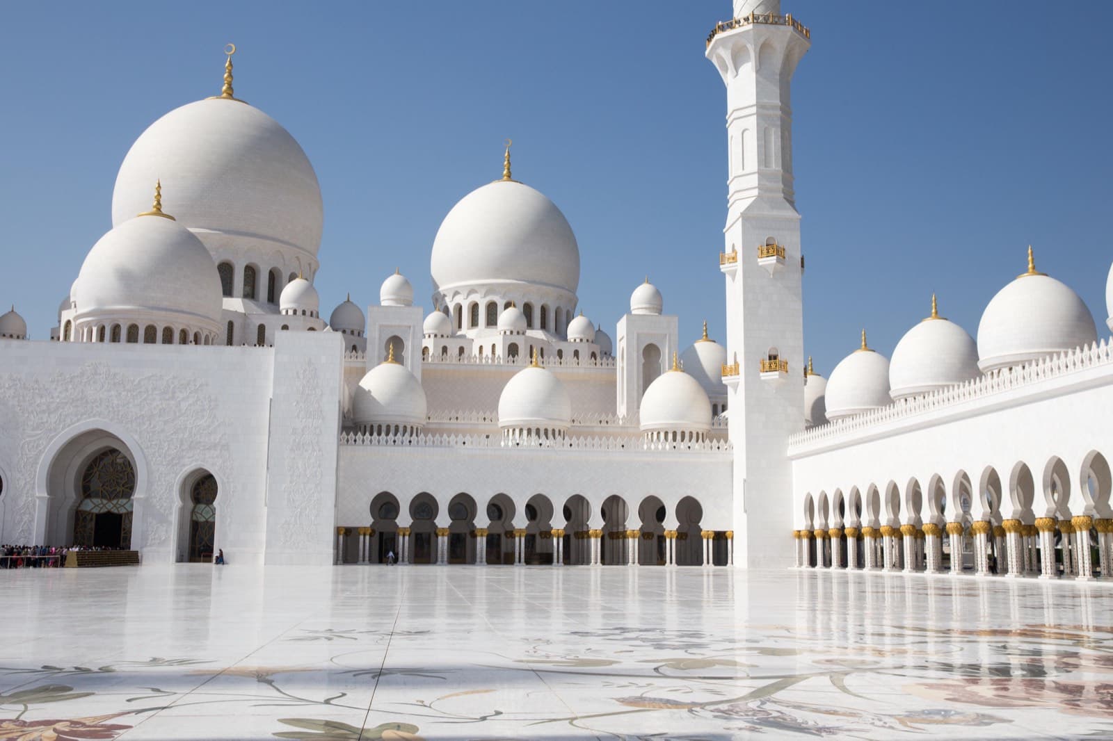 Bílá mešita s minaretem a kopulemi v Dubaji za slunečného dne