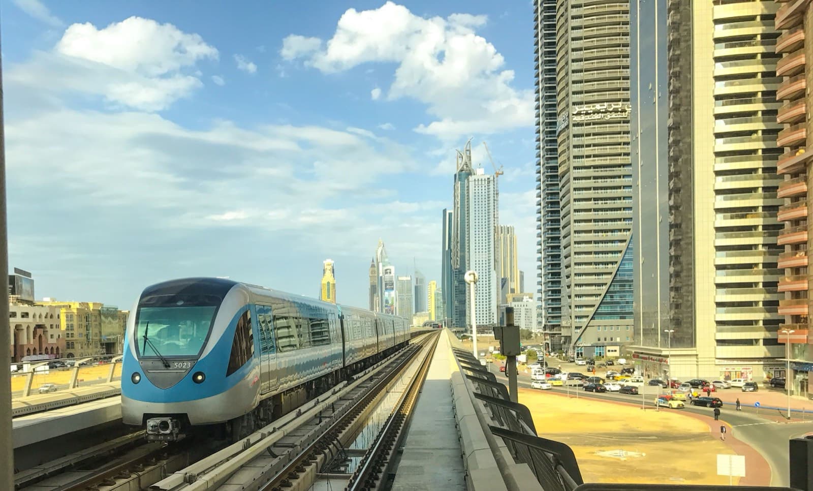 Souprava dubajského metra přijíždí po nadzemní trati s mrakodrapy v pozadí